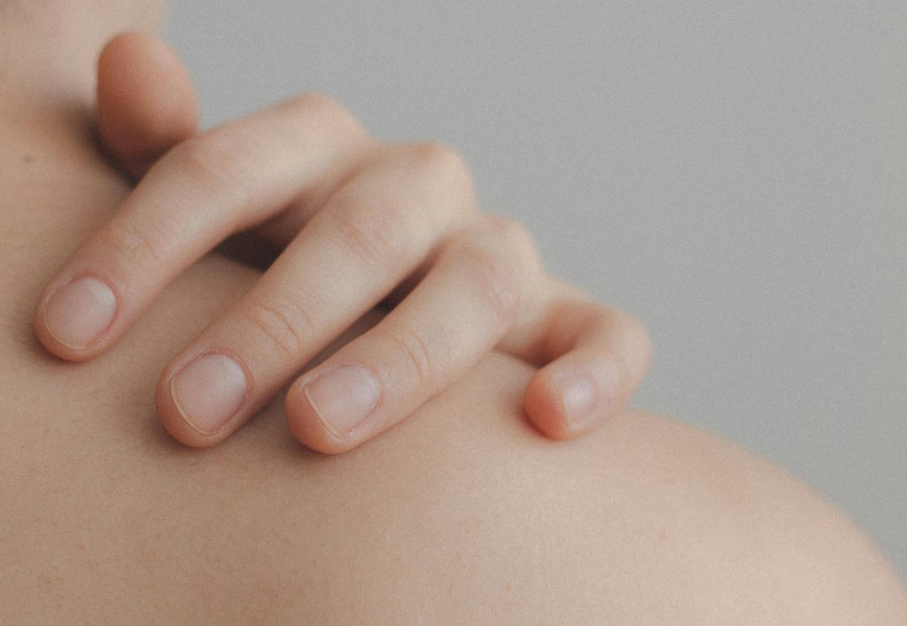 A gentle close-up of a hand resting on a person's shoulder, emphasizing skin texture.
